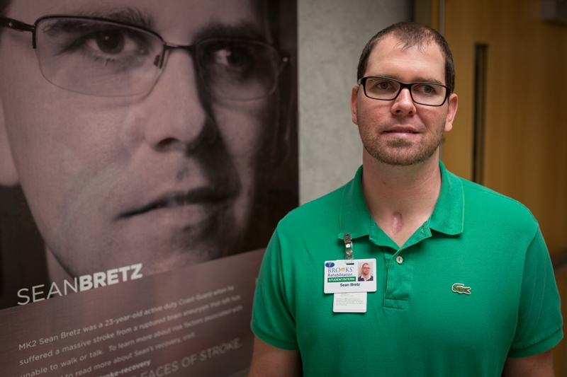 Sean standing next to his faces of stroke poster