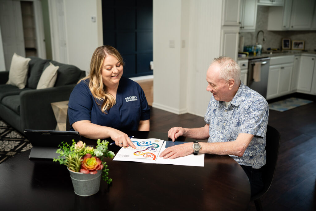 patient and therapist sitting at table reading brochure