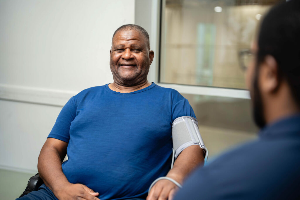 Man sitting and smiling while getting blood pressure done