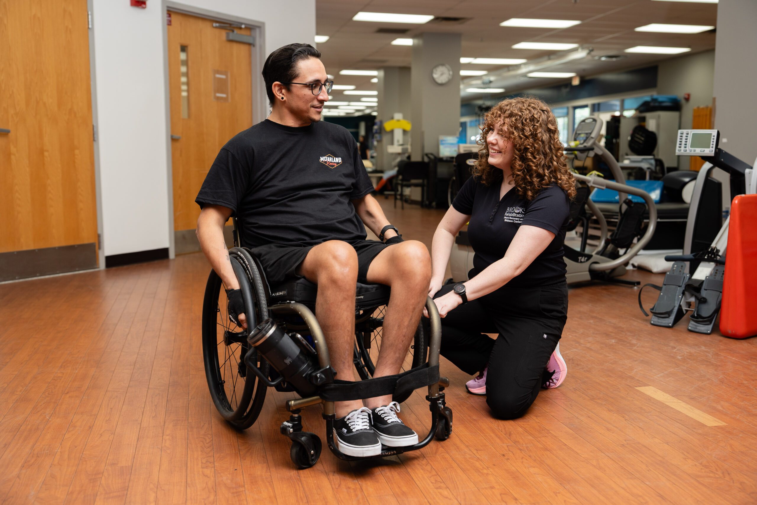 a woman occupational therapist adjusts the wheelchair of a young male patient.