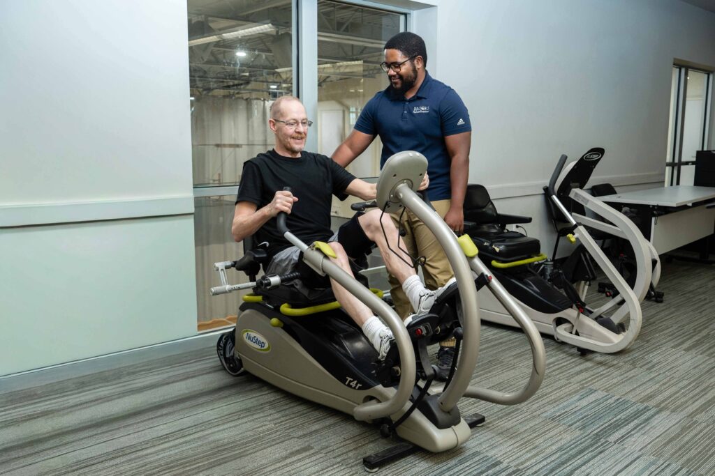 Therapist helping patient on exercise machine