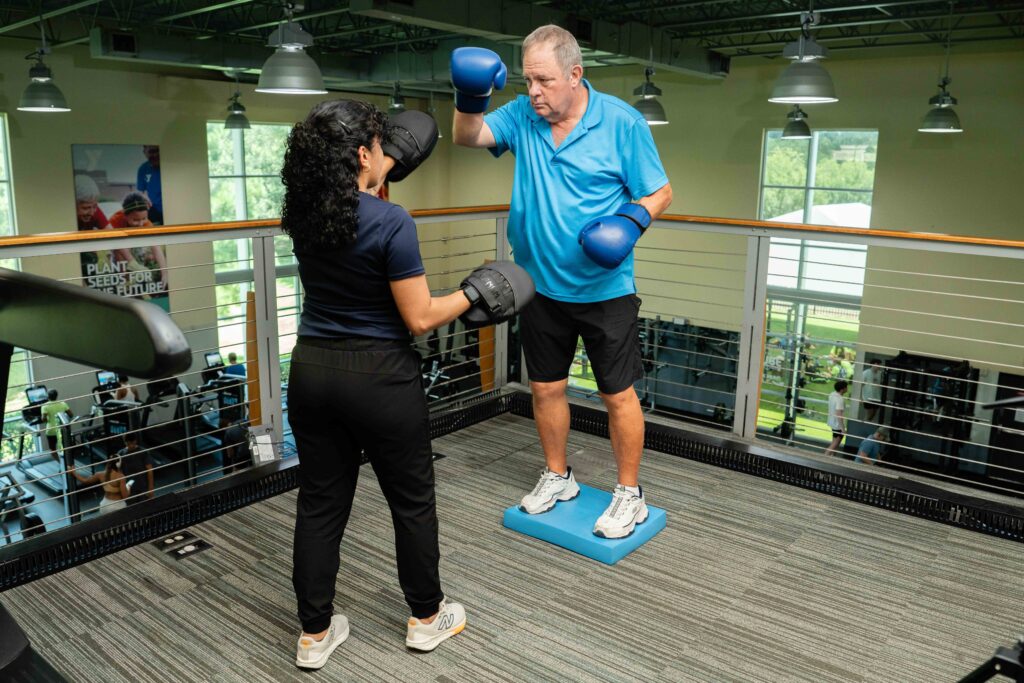 patient boxing with adaptive equipment with therapist