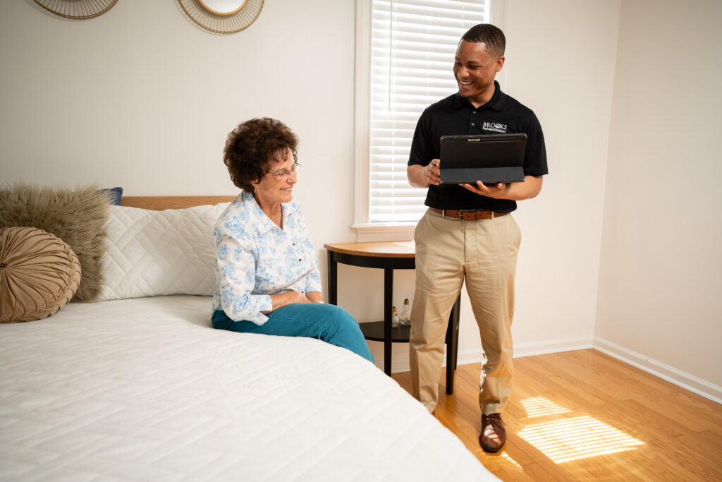 home health therapist holding iPad and talking to patient sitting on bed