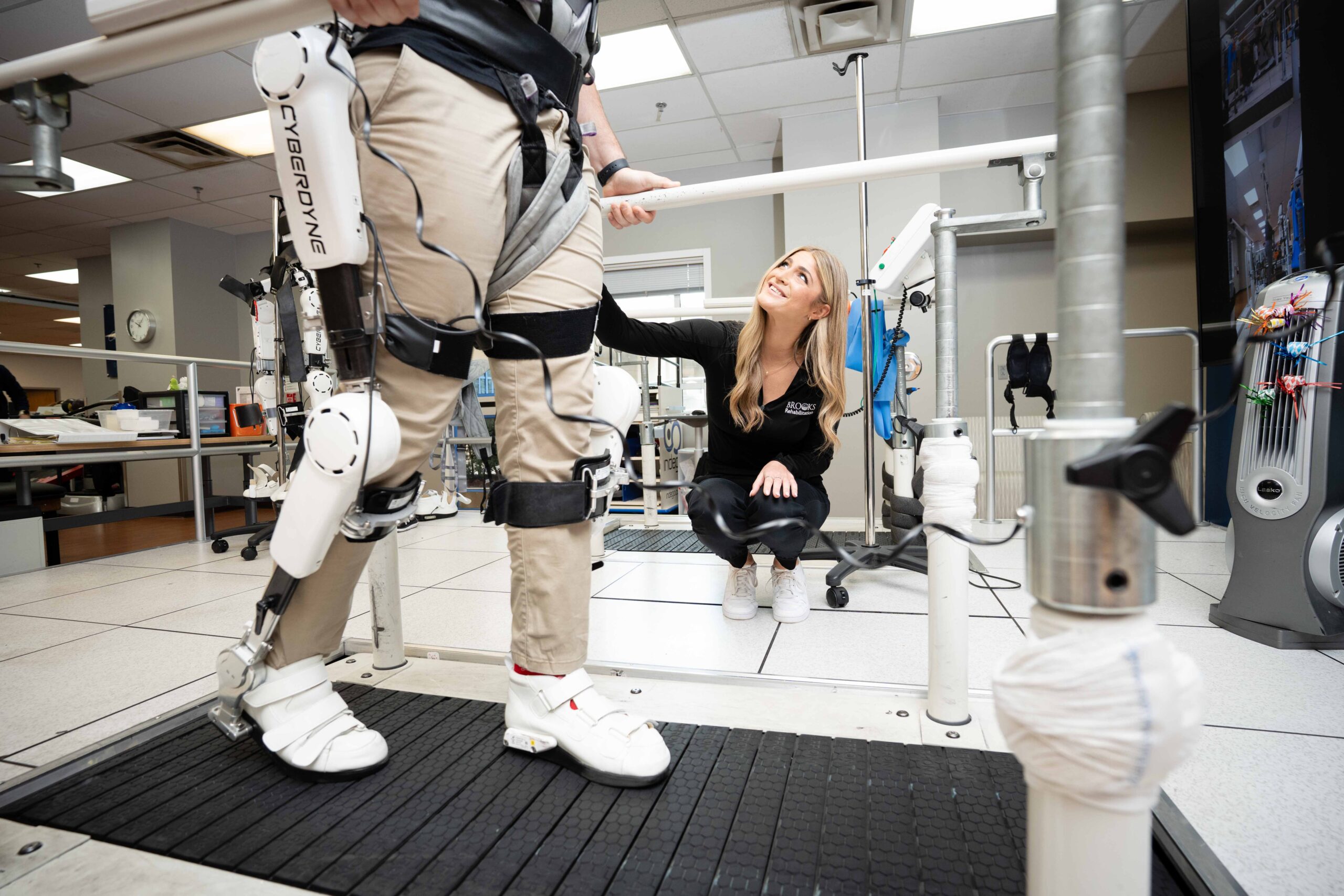 patient walking on treadmill with technology and therapist helping