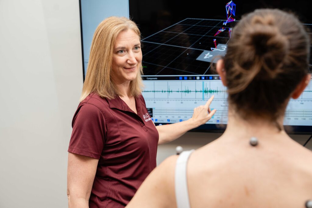 clinician reviews movement data on a screen with an athlete