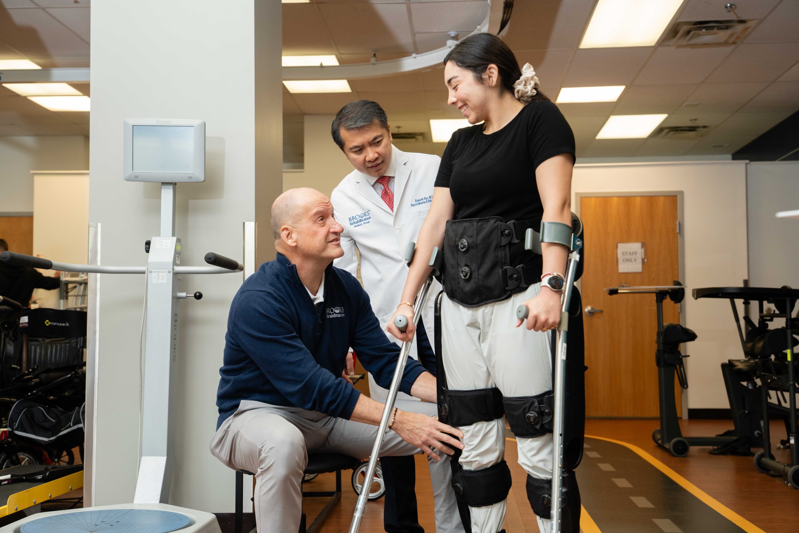 woman standing in braces and crutches with doctor and therapist helping