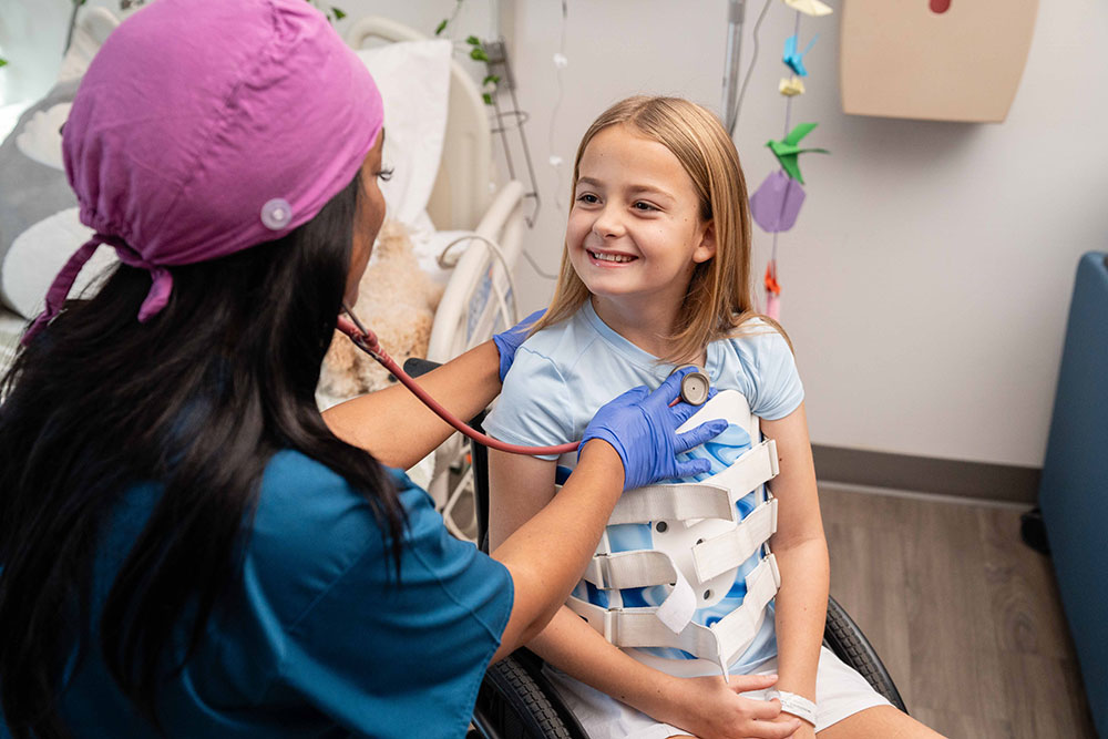 Brooks Rehabilitation nurse listening to a young girl's breathing