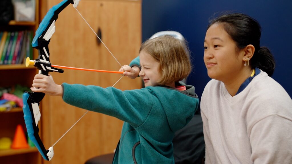 Pediatric patient participating in archery for pediatric recreation.
