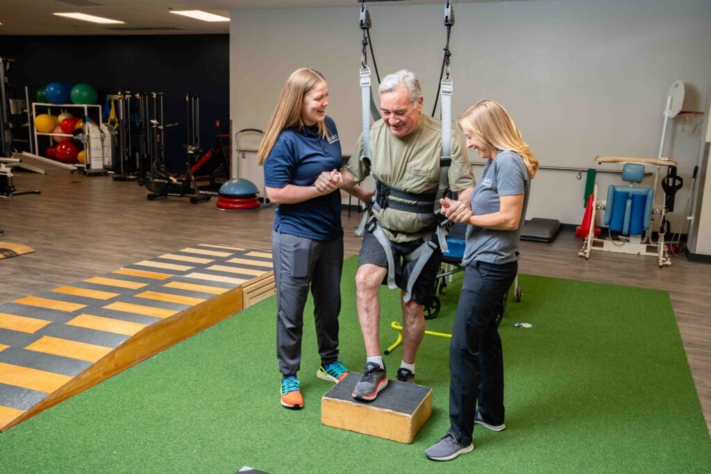 Two physical therapists in the SCI Day Program help a patient walk with a Zero gravity harness.