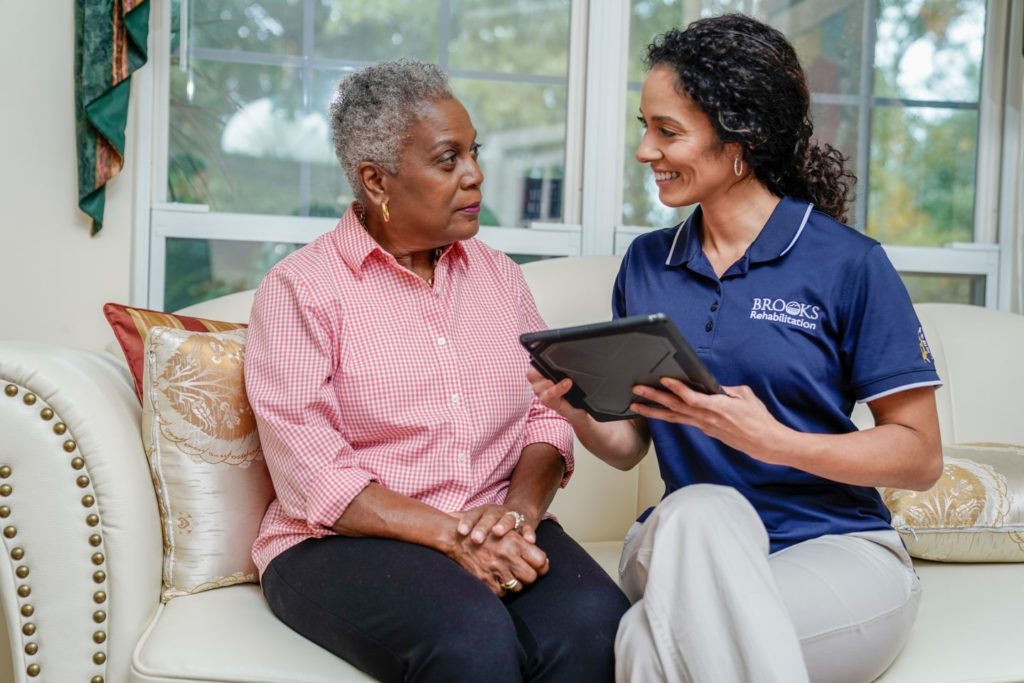 home health case manager sits with elderly patient in their home.