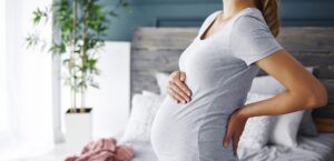 A pregnant woman holds her stomach and her back