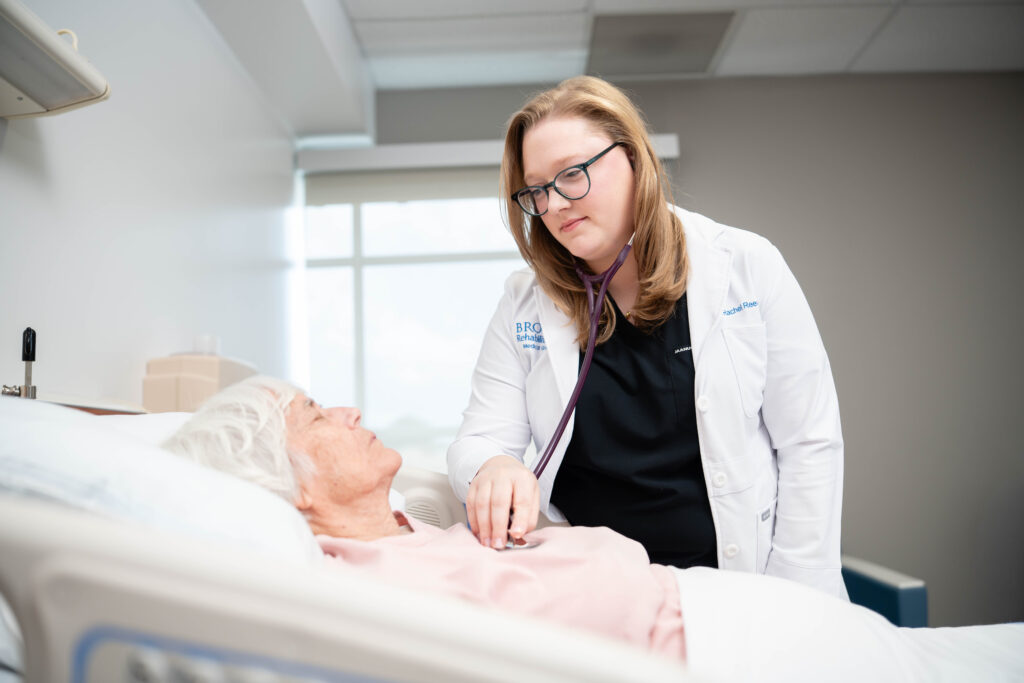 PM&R physician checking a patient's vitals in their hospital room.