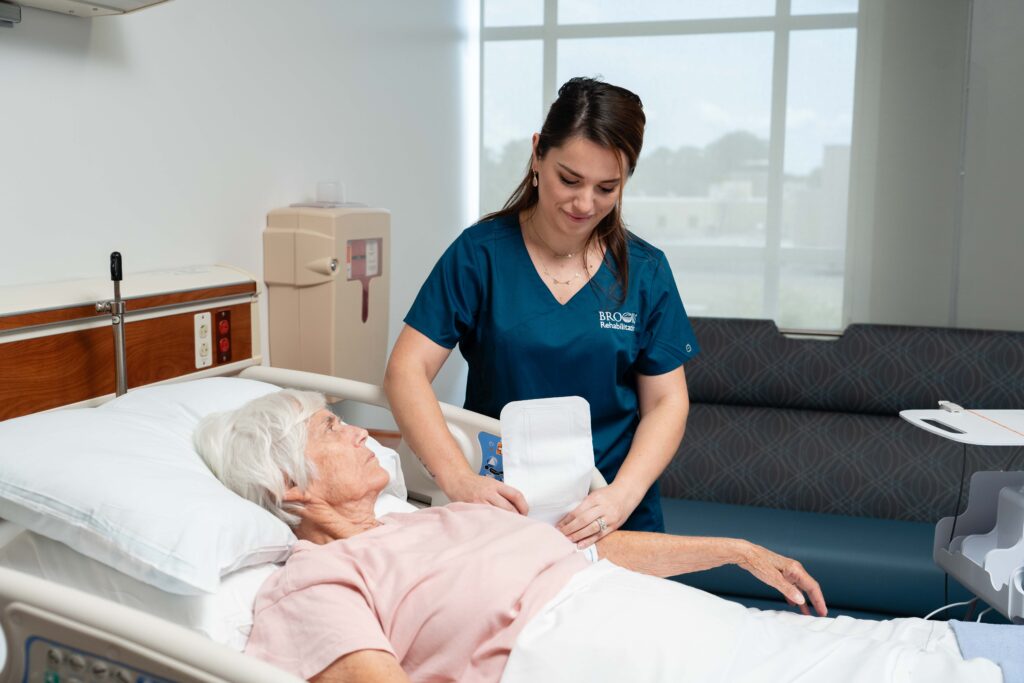 A rehabilitation nurse puts a blood pressure cuff on a DoC patient in the hospital bed.
