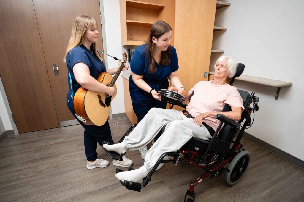 A music therapist plays a guitar for a patient in the Brooks' DoC program.
