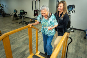 A therapist at Brooks Rehabilitation Clinic helps a patient excercise on stairs.