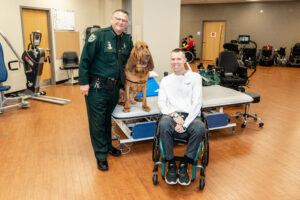 In the Brooks Rehab Clinic, Chris Streiff poses with Sheriff and their K9 deputy