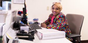 Employee at a desk smiling at the camera