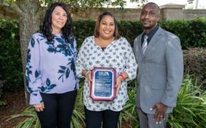 Valencia Henderson posing with her Nurse of the Year Award and two other people