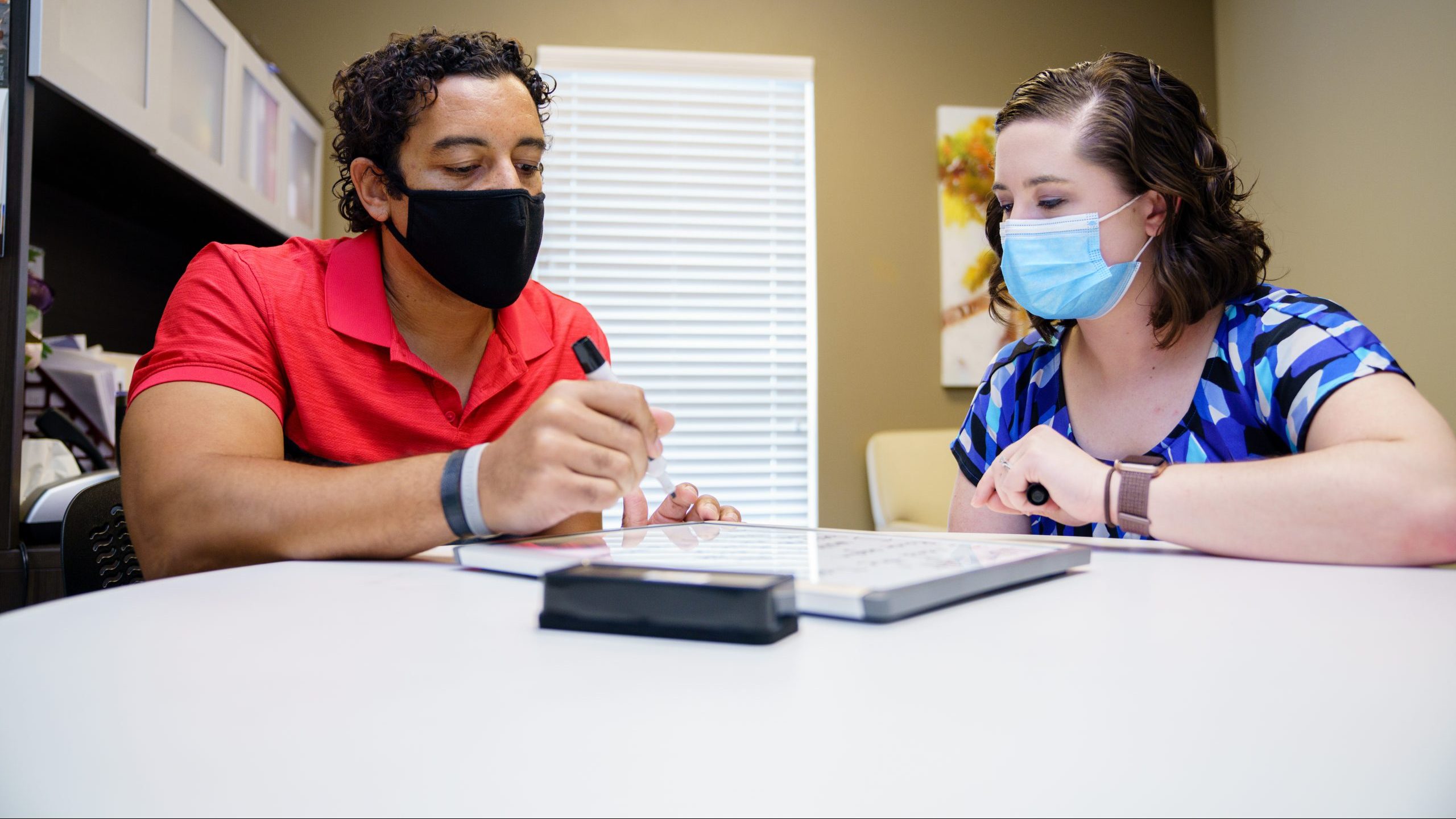 Patient using a whiteboard while talking to staff