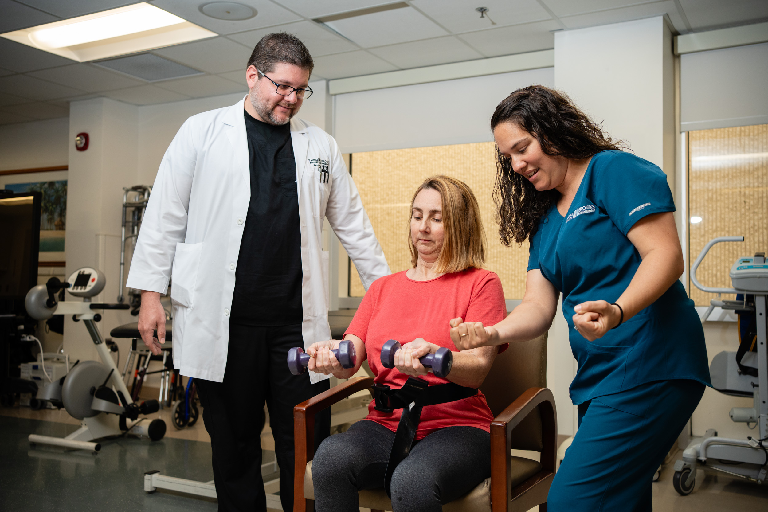 Patient holding weights with therapist and doctor