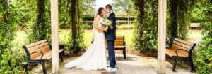 The bride and groom kissing under the ceremony arch