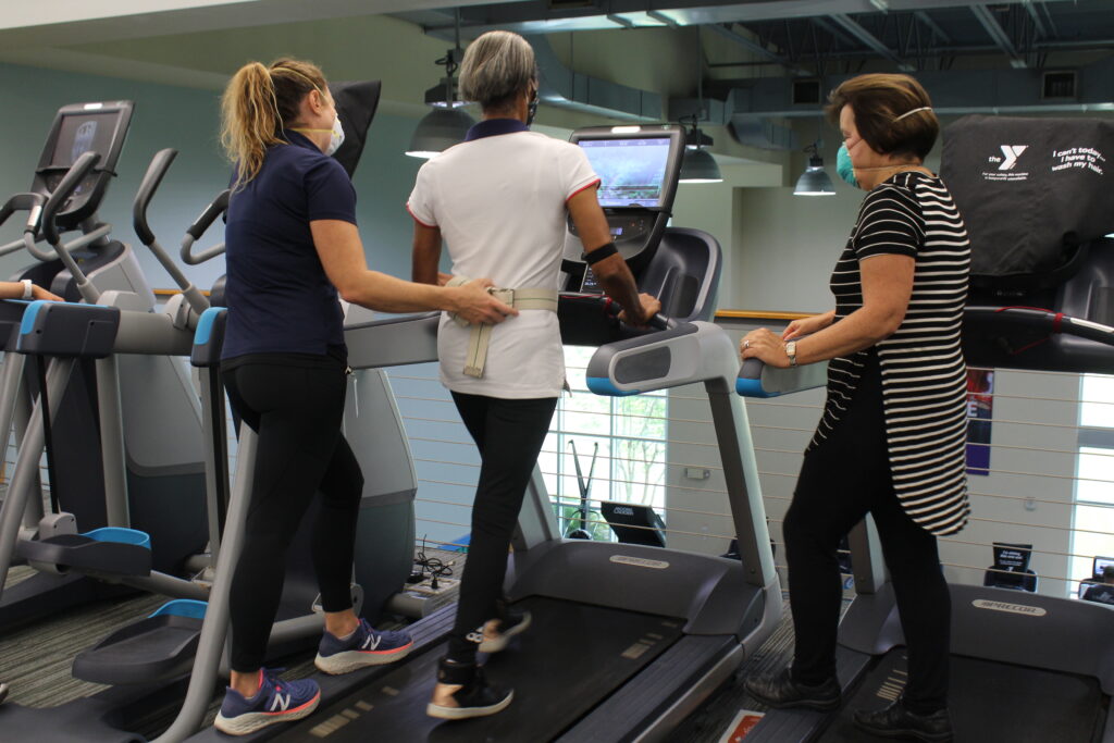 Patient walking on a treadmill being lightly supported by a staff member