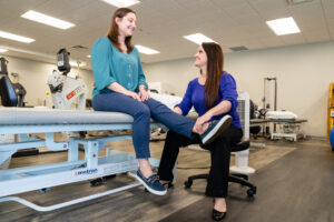 Therapist examines patient's leg at Metrowest Outpatient