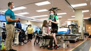 Spinal Cord Injury survivor Declan Graham walking while being supported from above and monitored