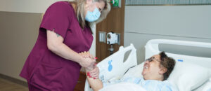 Brooks CNA holding a smiling patients hand