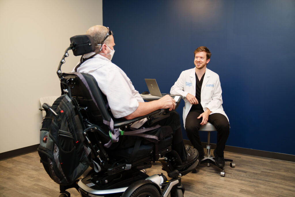 Dr. Brian Higdon consulting with a patient in an electric wheelchair