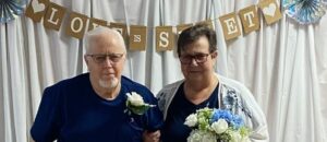 Joe Navarro and Sally Tucker posing for a wedding photo, Sallly holding flowers