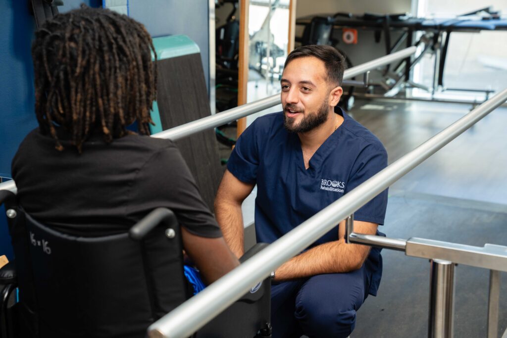 therapist discusses treatment with pediatric patient in a wheelchair.
