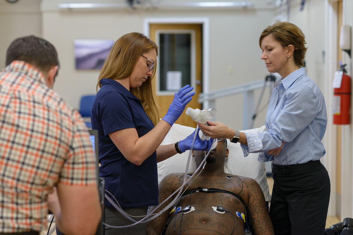 Emily Fox, PhD, works with a Brooks researcher providing breathing therapy to a patient with a spinal cord injury.