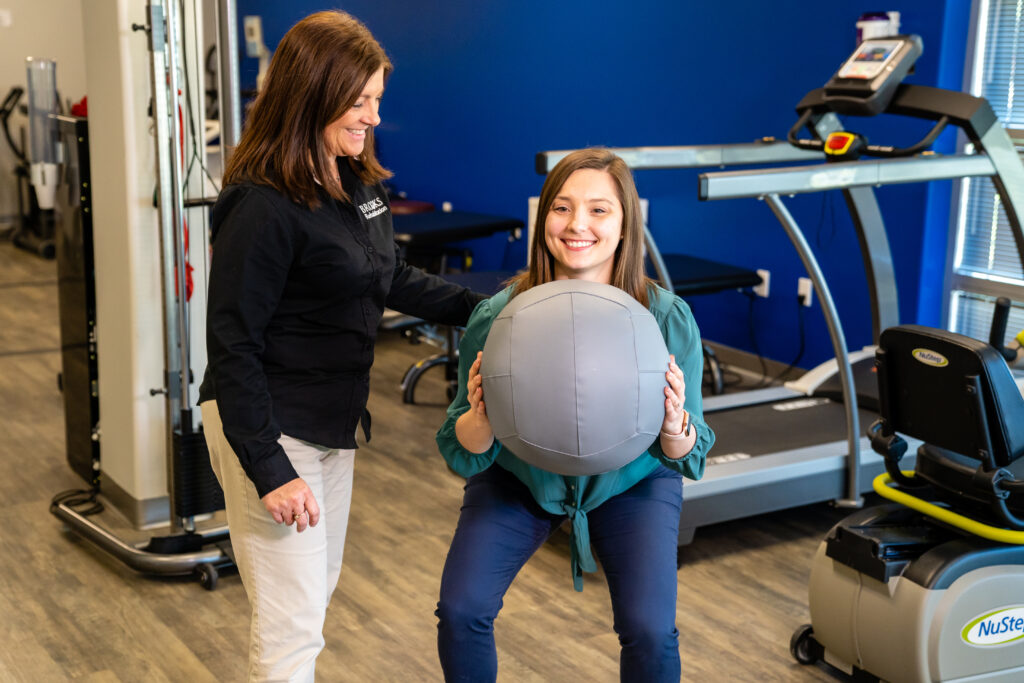 Patient using a medicine ball with help from a therapist