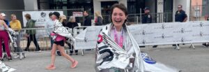 Sam Carter wrapped in a space blanket and smiling after marathon