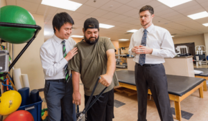 Two physical therapists assist a patient while exercising