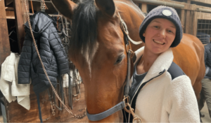 Laura Ray poses with horse in stable.