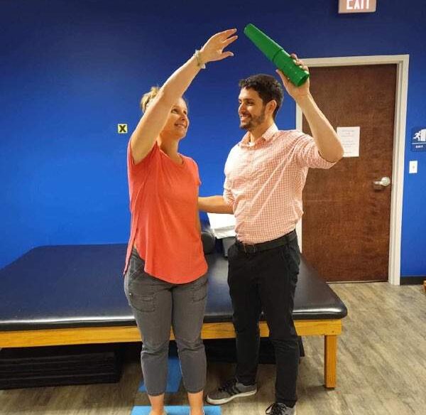 Brooks clinician works with patient by having them reach above their head.