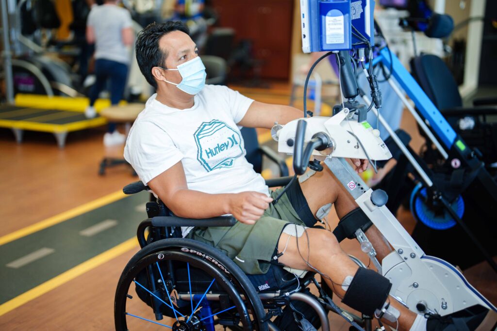 SCI survivor working out on an adaptive bike in the neuro recovery center.