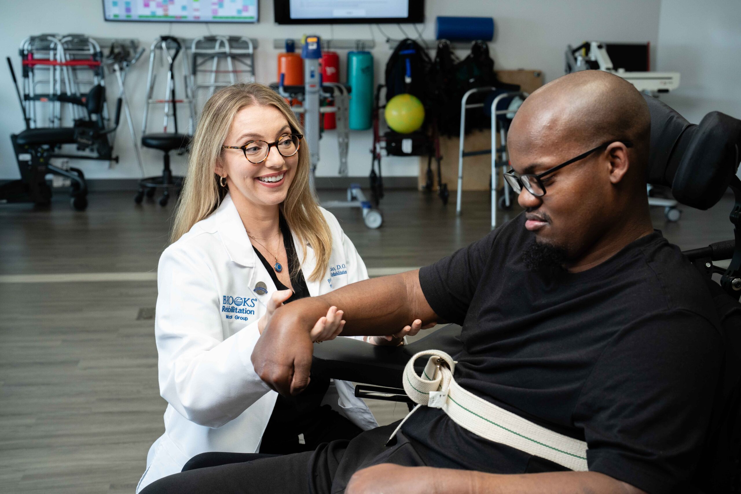 A PM&R doctor at Brooks assesses the strength of a patient recovering from a traumatic event in a therapy gym. 