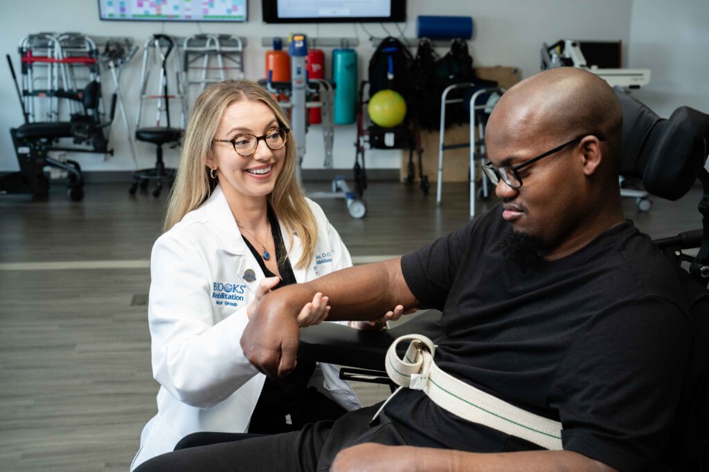 Dr. Tribuzio of Brooks oversees a patient in wheelchair's physical therapy progress.