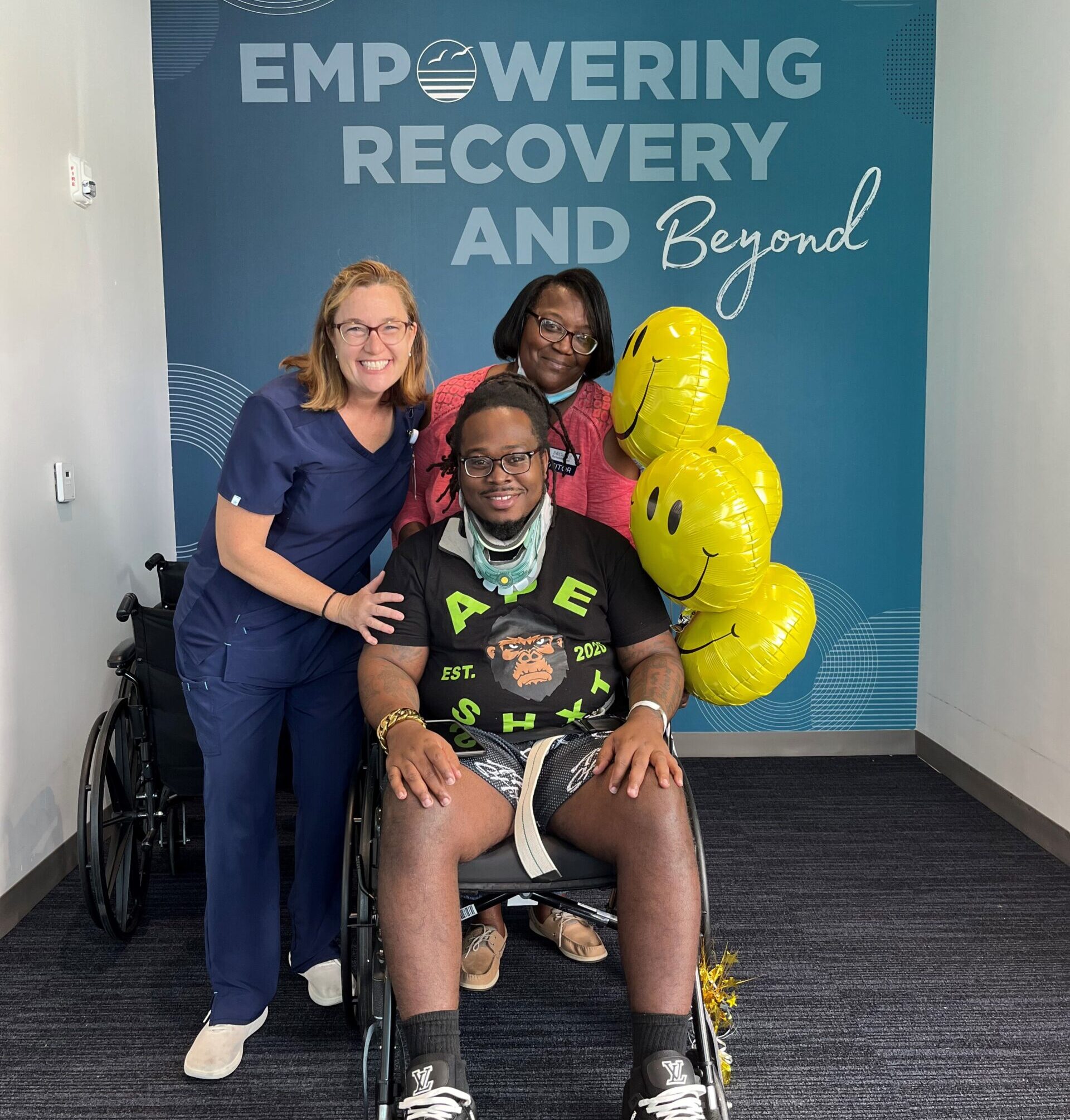 Zay Brown in a wheelchair with his therapists at Brooks Bartram Hospital campus. 