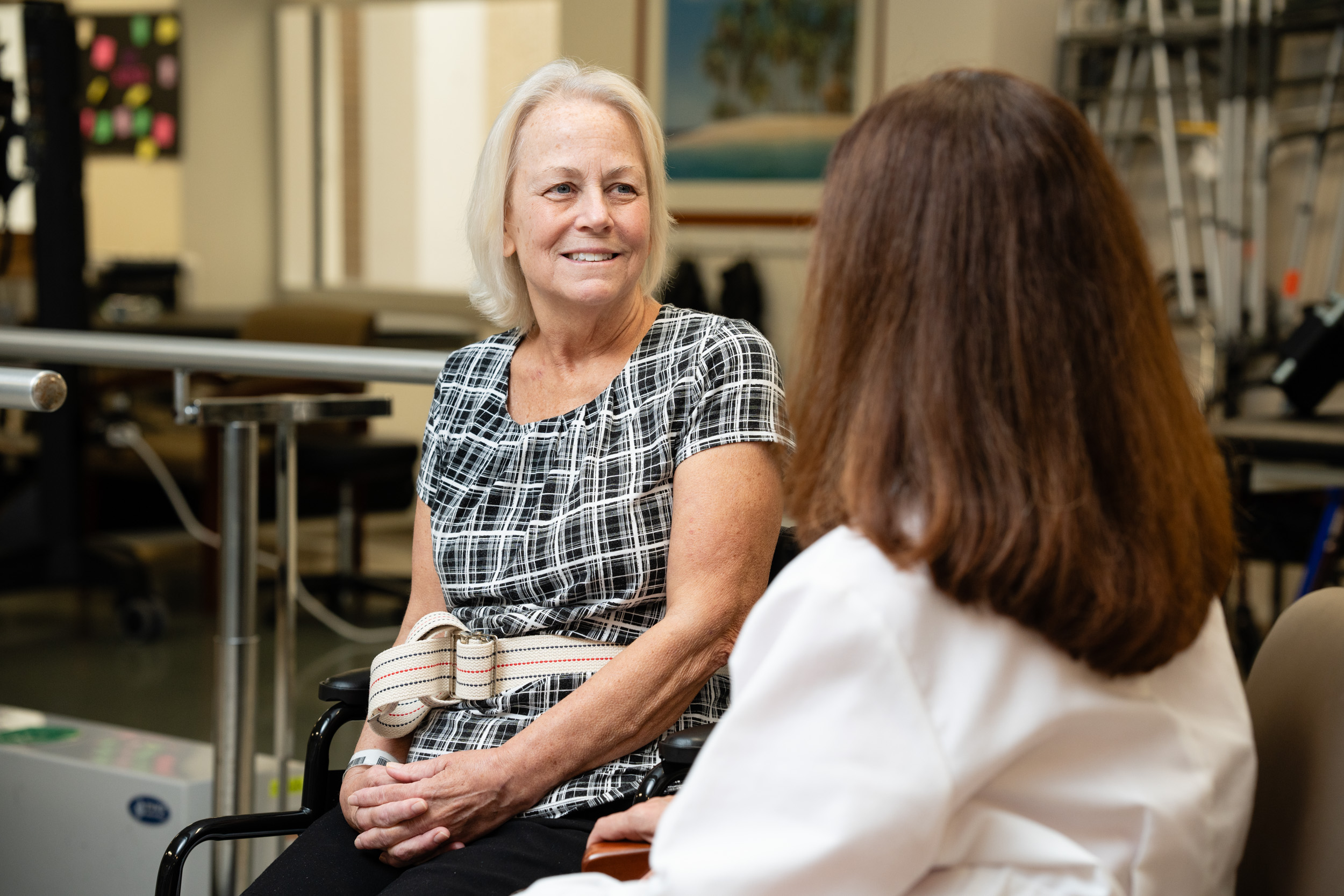 a patient with a walking belt sits in a hospital gym receiving a doctor consult.