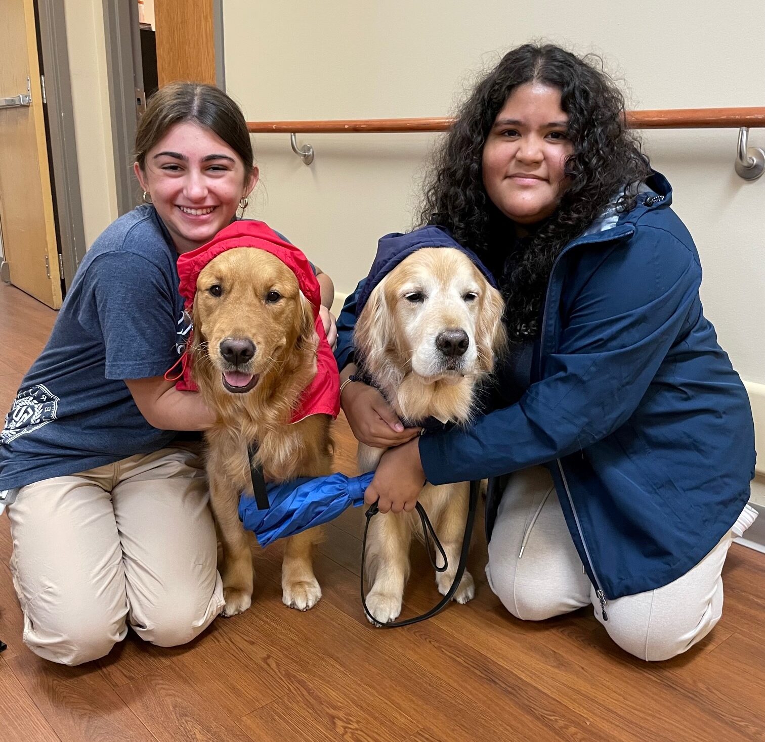 two teen volunteers hug service dogs at Brooks Rehabilitation.