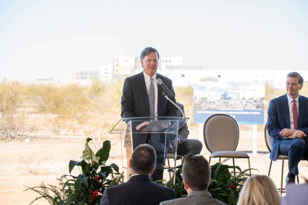 Doug Baer, president/CEO, Brooks Rehabilitation, stands at podium with mic.