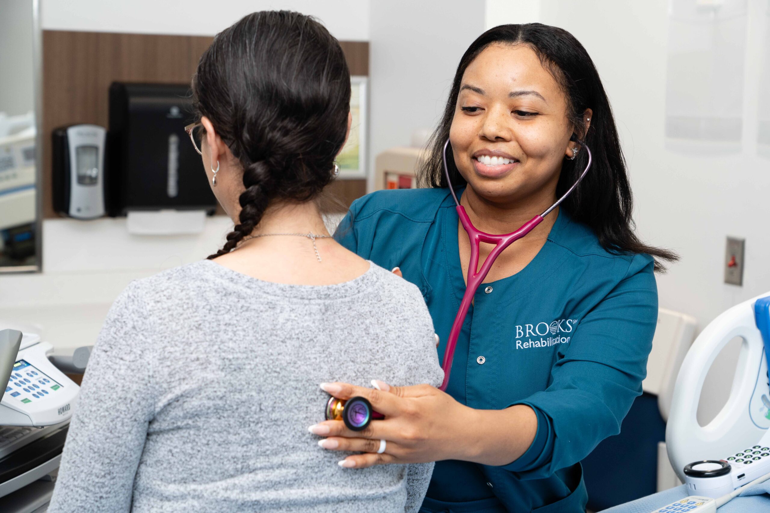 a nurse at brooks hospital checks the heartbeat of a patient.