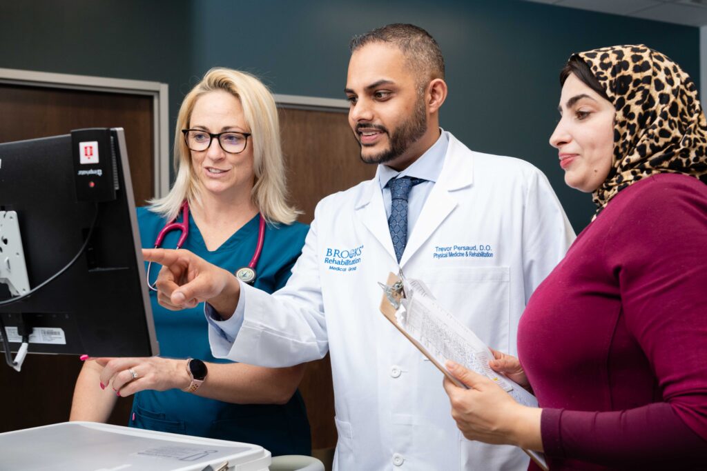 brooks doctors, nurses and therapists observe a patient chart on a computer screen.