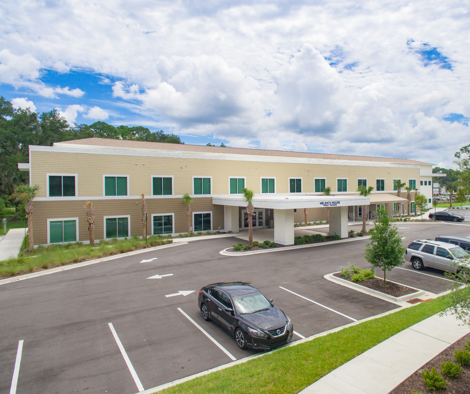 Exterior photo of a light brown building and parking lot.