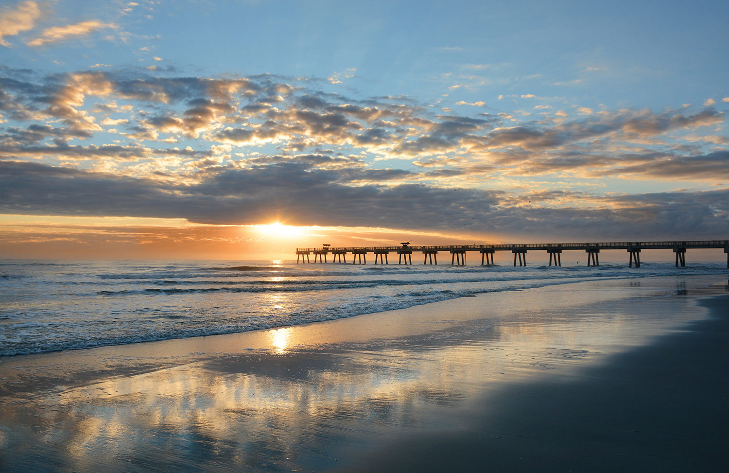 Beautiful sunrise over ocean horizon and pier.