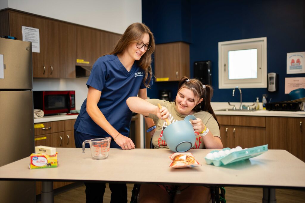 pediatric rehabilitation patient makes cookies in a sim lab with a therapist.